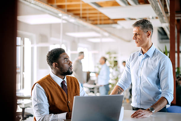 istock Two diverse male colleagues discussing work using laptop in office 2247136520