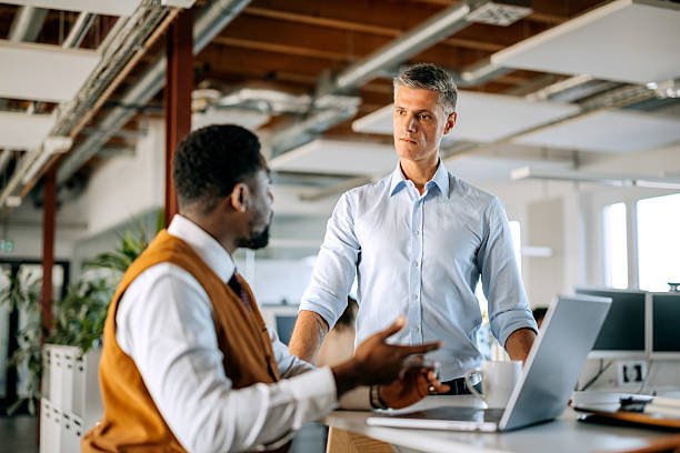 istock Two diverse male colleagues discussing work using laptop in office 2247136531
