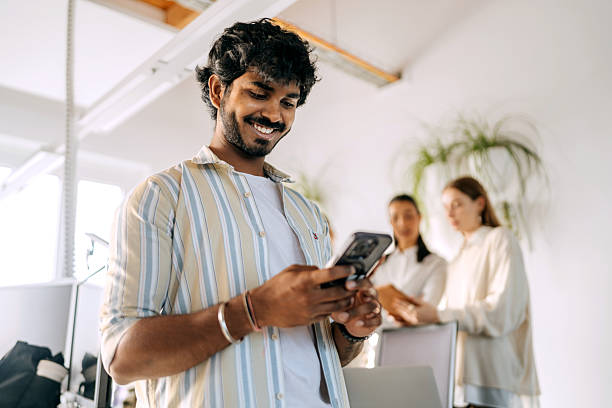istock Young cheerful businessman using smart phone at the office 2247136873