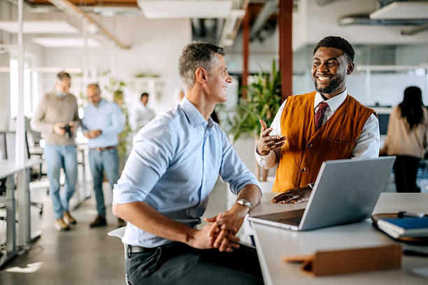 istock Two diverse male colleagues discussing work using laptop in office 2247137217
