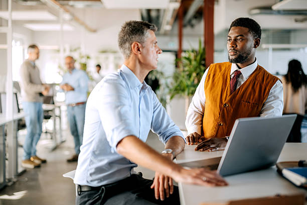 istock Two diverse male colleagues discussing work using laptop in office 2247137219