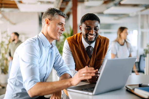 istock Two diverse male colleagues discussing work using laptop in office 2247137310
