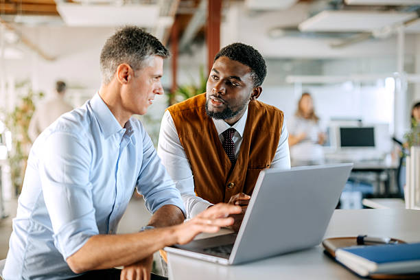 istock Two diverse male colleagues discussing work using laptop in office 2247137354