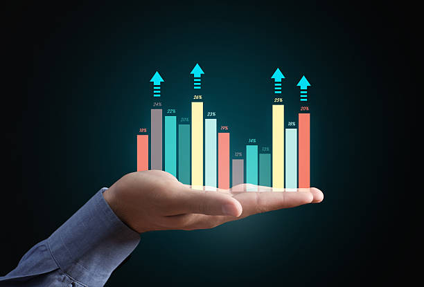 Hand holding a holographic bar chart with upward arrows, symbolizing data analysis, financial growth, and successful investment