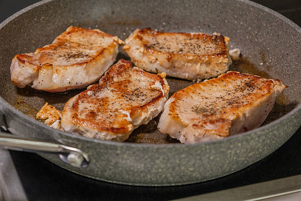 juicy pork chop cooking in a hot pan on the stove. sizzling meat, golden crust, and home cooking atmosphere. perfect for recipe content, food preparation, cooking process, kitchen visuals, and culinary tutorials.