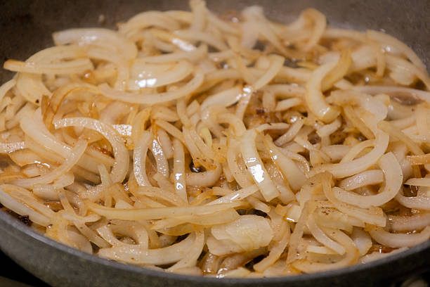 onion slices slowly caramelizing in a hot pan. golden, sweet, sizzling onions perfect for cooking tutorials, recipe videos, meal preparation visuals, and kitchen content. rich aroma, home cooking, and close-up food process
