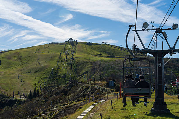 Shiga Prefecture, Japan - October 22, 2023: Tourists and visitors enjoy the scenic view from the Biwako Valley mountain top. The scene includes the vast green grassland, the cable car leading to the peak, and numerous people enjoying a summer day. The Biwako Valley Ropeway is a popular tourist destination, offering panoramic views of Lake Biwa.