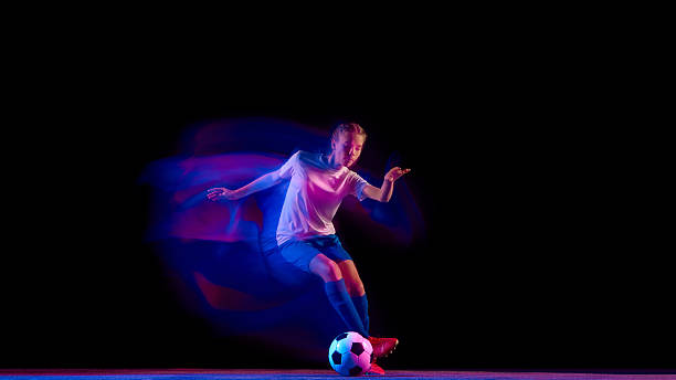 istock Female football player controlling ball with precision under lights. 2247140429