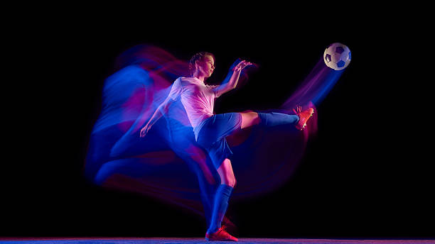 istock Female soccer player striking ball in motion blur with neon trail 2247140439