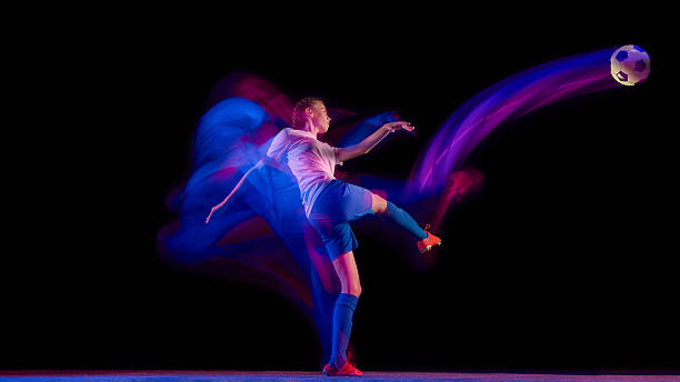 istock Female athlete kicking soccer ball with dynamic light trail 2247140451