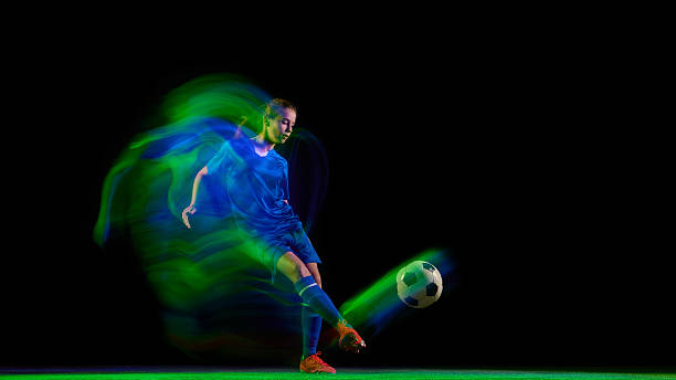 istock Female soccer player running with glowing orange and violet light trail 2247140457