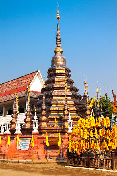 Thai pagoda and stupa at Wat Phan Tao in Chinag Mai inner old city. Pagoda has two texts placed at it and is decorated with thai wheel symbol flags