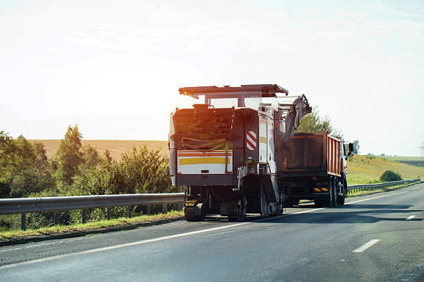 istock A special road-cutting machine, specifically designed for cutting asphalt layers, cuts asphalt into a dump truck with asphalt chips. Country road repair. Copy space for text 2247147359