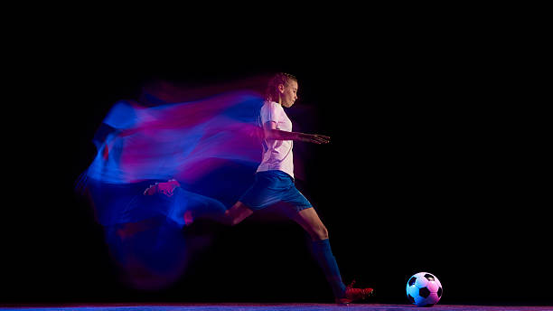 istock Female soccer player preparing for powerful strike in neon lights 2247147396