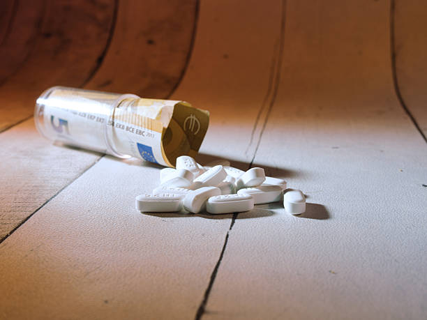 istock Medicine Cost: Pills and Euro Banknote - White pills spill from a container with a 5 Euro banknote, symbolizing the high cost of medication, healthcare expenses, and drug addiction. 2247149015