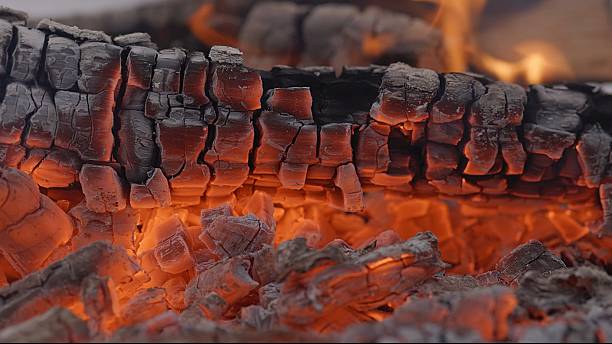 Close-up of Hot Embers with Flying Sparks . Concept of heating Fireplace