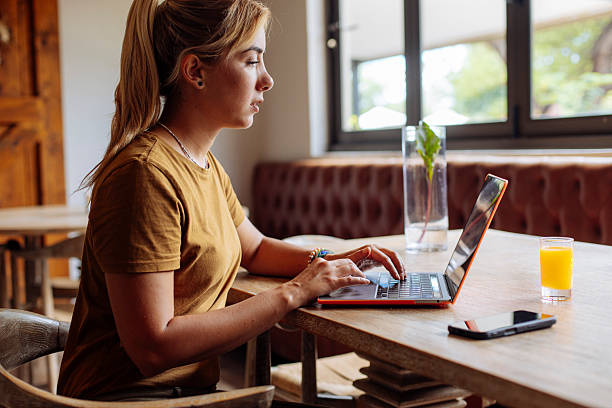 istock Focused Woman Working On Orange Laptop In Cozy Cafe Setting For Remote Work 2247157012