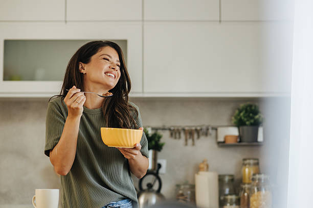 istock Happy woman enjoying healthy breakfast cereal in kitchen 2247158472