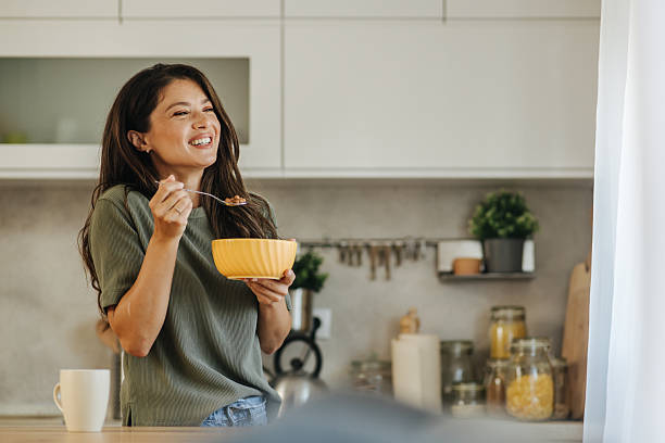 istock Woman smiling and eating cereal in her modern kitchen 2247158479