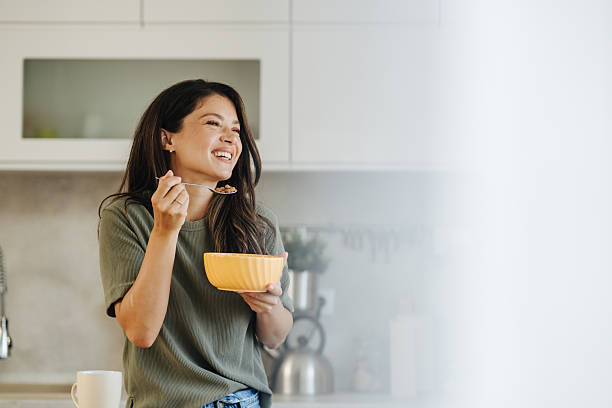 istock Happy woman eating healthy breakfast cereal in kitchen 2247158512