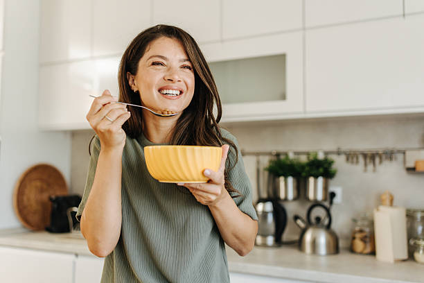 istock Smiling woman eating healthy breakfast cereal in kitchen 2247158517