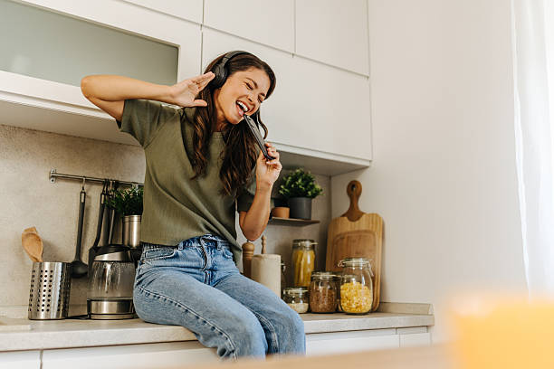 istock Woman enjoying music singing holding smartphone in kitchen 2247158597