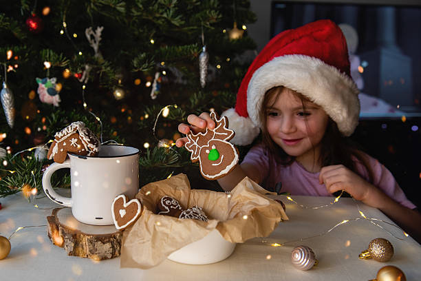 Little girl wearing Santa hat holding gingerbread reindeer