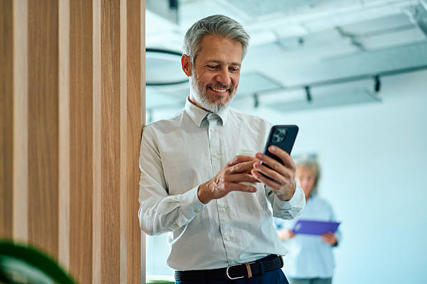 istock Mature businessman smiling and using smartphone in modern office 2247160083
