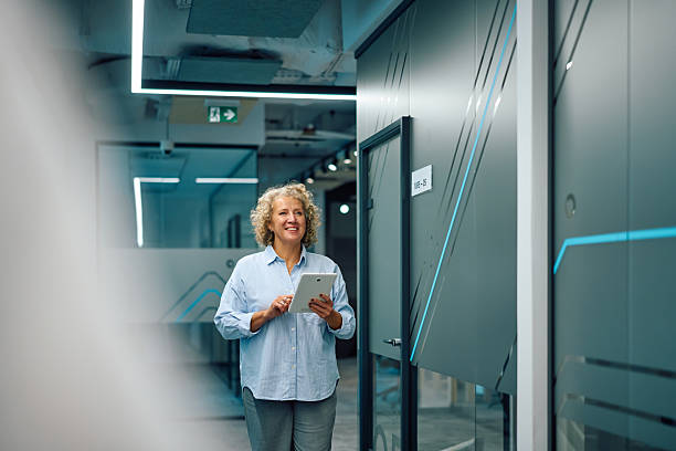 istock Senior businesswoman walking in modern office using digital tablet 2247160201