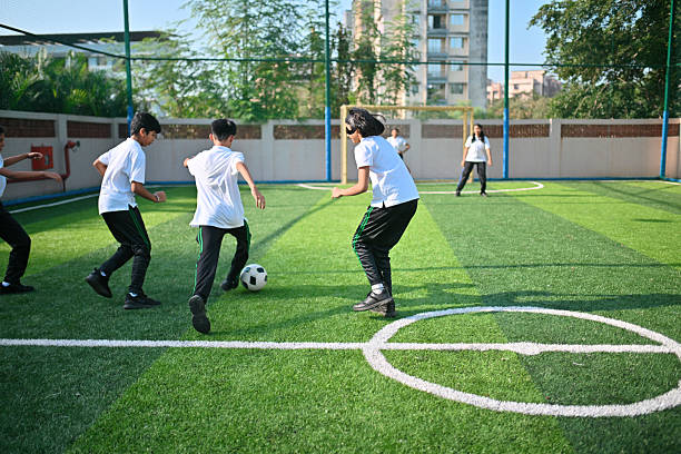 Middle school boys and girls run together during an energetic outdoor soccer game on the green field.