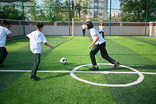 Middle school boys and girls run together during an energetic outdoor soccer game on the green field.