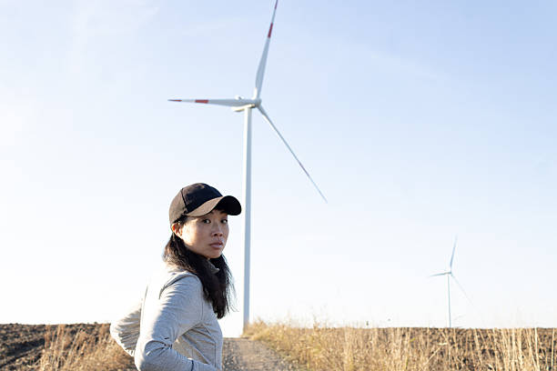 istock Woman standing by wind turbines generating clean energy 2247160424