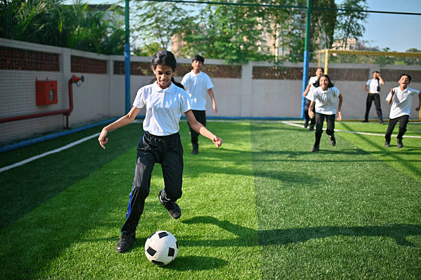 Middle school players chase the ball and move across the field, fully engaged in a lively sports game.