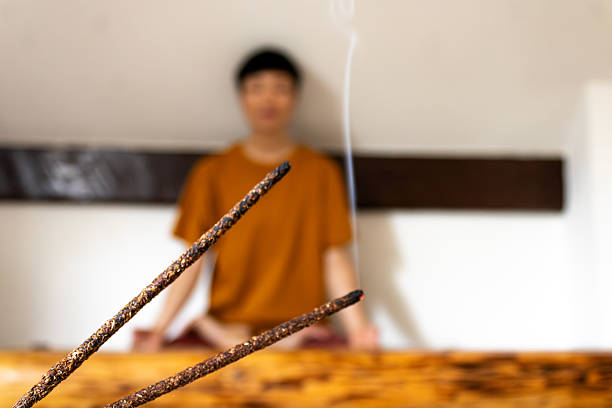 Person meditating in a calm setting with aromatic incense smoke rising