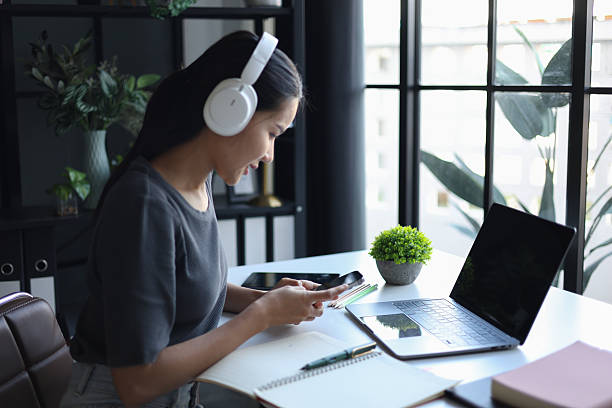istock Happy beautiful women wearing headphone, using phone, tablet, working on desk. 2247164012
