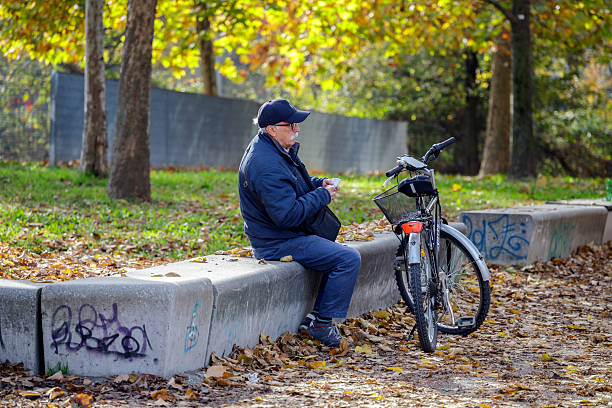 Turin, Piedmont, Italy - November 6, 2025: An elderly man with a bicycle in a public park in autumn.