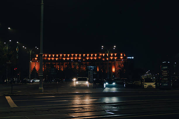 Bucharest, Romania - 11/15/2025: Car traffic on the main boulevard at Victoria Square at night in Bucharest downtown
