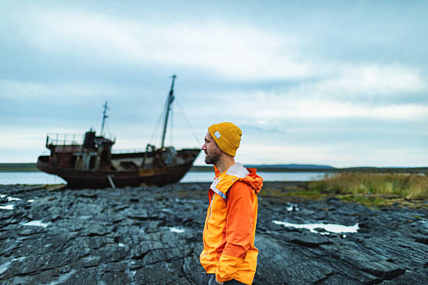 istock Mid adult brutal man with old rusty ship at background 2247169185
