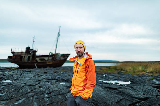 istock Mid adult brutal man with old rusty ship at background 2247169461