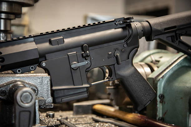 istock Black AR-15 style rifle receiver close-up on industrial metal machinery in a workshop setting. 2247172082