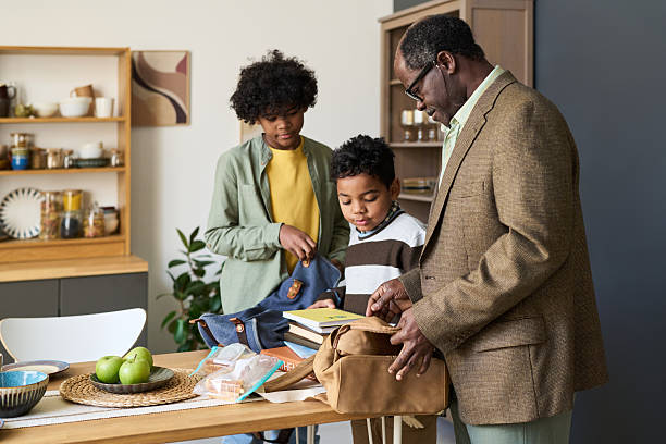 istock Mature Black Man Helping Two Children Packing School Bags in Kitchen 2247173089