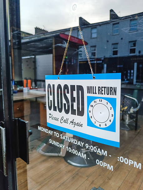 istock Closed sign on cafe door with empty seating inside and city reflections 2247173844
