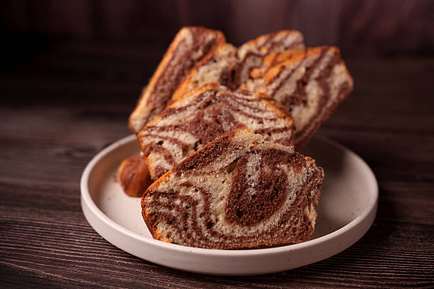 istock close-up of sliced marble cake on white plate with swirling chocolate and vanilla patterns, set against dark wood background, capturing a cozy and inviting atmosphere, treat, tempting, indulgent 2247173924
