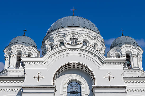 Symmetrical facade of a domed Orthodox church with ornate details and bright stucco. Kaunas, Lithuania