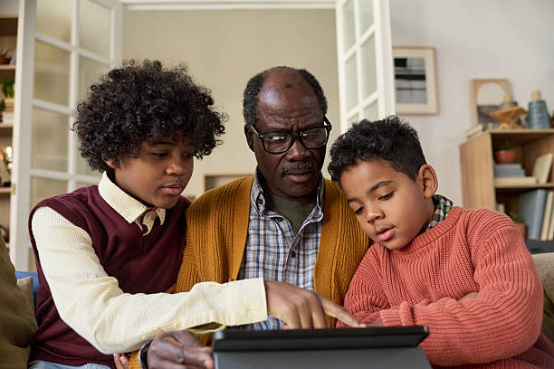 istock Senior Black Man Teaching Two Black Boys Using Digital Tablet at Home 2247176750