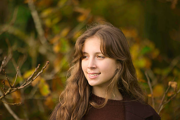 Sixteen year old girl wearing brown by an old oak tree.