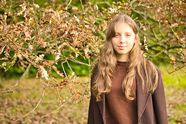Sixteen year old girl wearing brown by an old oak tree.