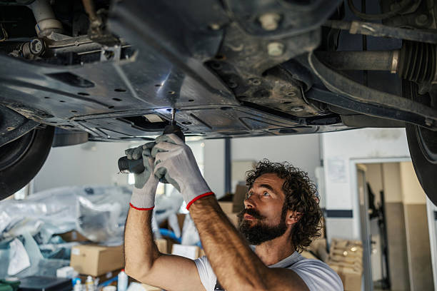 istock Mechanic inspecting undercarriage of lifted car in workshop 2247184182