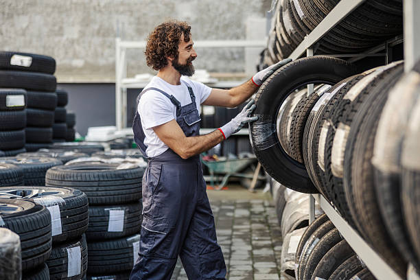 istock Auto mechanic placing new car tire on shelf 2247184253