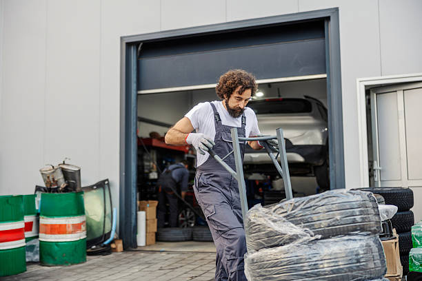 istock Mechanic man pushing dolly with tires at workshop 2247184288